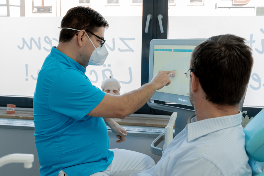 Zahnarzt Reinhard Huber bei der Beratung eines Patienten | Ortho Smile in Nürnberg